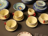 many plates and cups on the table with forks and spoons
