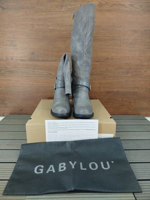 des bottes en cuir gris exposées devant une boîte contenant un sac noir