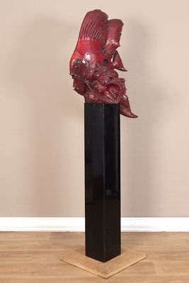 sculpture représentant un poisson rouge posée sur un socle noir, posée à son tour sur un plancher en bois