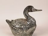 an image of a metal duck sitting on top of a white surface