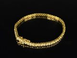a yellow gold bracelet with diamonds on a black background
