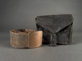 une vieille ceinture en cuir avec une boucle en métal, à côté d'une pochette en cuir