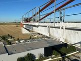 an aerial view of a bridge over a field with cars parked on the side of it