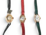 three different colored watches are lined up on a white surface