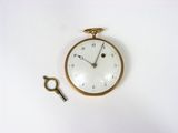 une horloge et une clé posées sur une surface blanche