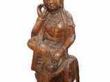 statue en bois représentant une femme assise sur un rocher, la main posée sur le menton