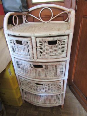 une commode en osier dans un coin de la pièce