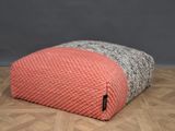 un pouf tricoté rose et gris posé sur un parquet