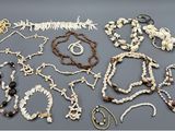 plusieurs colliers et bracelets posés sur une table, à côté d'une paire de ciseaux