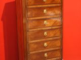 a tall wooden chest of drawers in front of a red wall