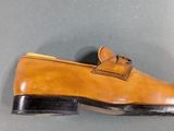 tan leather shoes with black soles on a gray surface