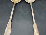 two silver spoons with handles on a black surface