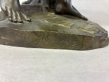 a bronze statue of a boy sitting on a rock