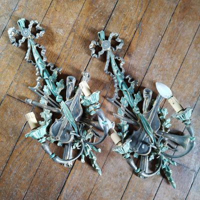 une paire d'appliques murales anciennes posées sur un parquet dans une pièce