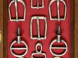 a lot of different types of metal buckles in a display case