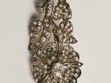 Une broche ancienne sertie de diamants est posée sur une surface blanche