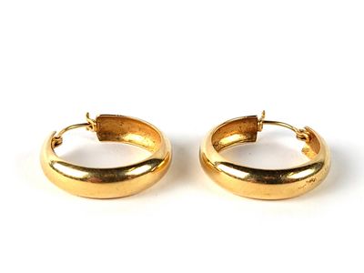 a pair of gold toned hoop earrings on a white background