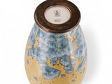 a blue and yellow vase sitting on a white surface