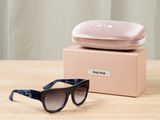 une paire de lunettes de soleil noires et bleues posée sur une table en bois