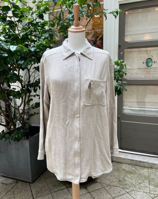La chemise est posée sur un mannequin devant une plante en pot