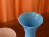 a blue vase sitting on a table next to a white bowl