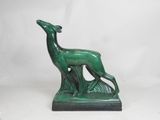 a green statue of a deer on a rock with a white background