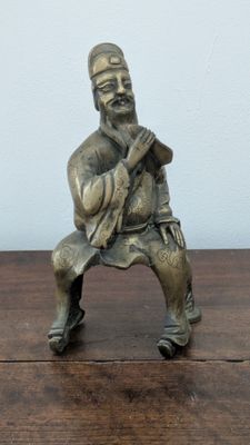 une petite statue représentant un homme assis sur un banc