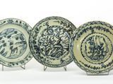 trois assiettes bleues et blanches ornées de motifs, posées sur un présentoir