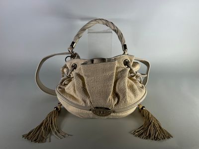cream colored purse with tassels and handles sitting on a white surface
