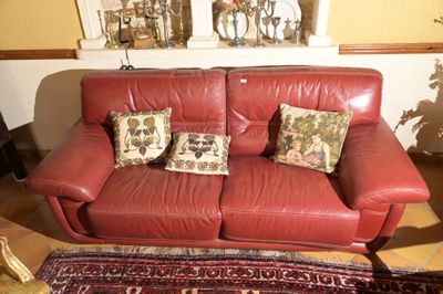 un canapé en cuir rouge avec deux coussins et un tapis au sol