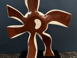 sculpture abstraite marron et blanche posée sur un socle noir, elle-même posée sur une table