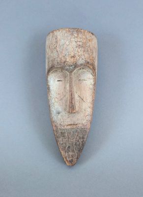 gros plan d'un masque en bois sur une surface grise