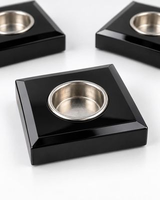 trois plats carrés noirs sur lesquels est posé un bol en argent