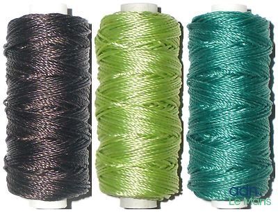 trois bobines de fil de différentes couleurs sur un fond blanc