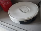 un robot blanc posé sur une étagère, à côté d'un extincteur