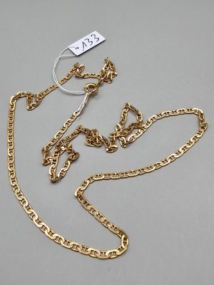 une chaîne en or à laquelle est accrochée une médaille, posée sur une surface grise