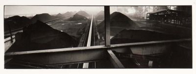 a black and white photo of a train going down the tracks