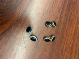 deux paires de boutons de manchette noirs et dorés posés sur une table en bois