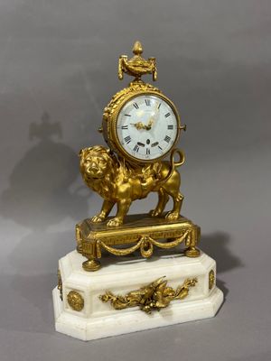 une horloge en or posée sur un socle en marbre orné d'un lion