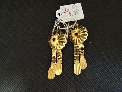 paire de boucles d'oreilles plaquées or ornées de fleurs sur un fond noir