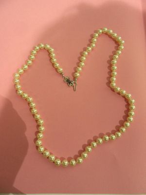 collier de perles orné d'un pendentif en forme de papillon sur fond rose
