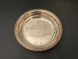 a silver plate on a black table with a picture on it