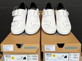 trois paires de chaussures blanches posées sur une boîte en carton