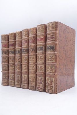 several old books are stacked on top of each other on a white surface