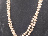 a white pearl necklace on a mannequin with a gold clasp