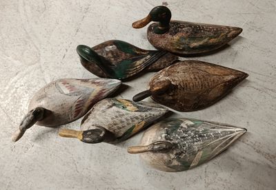 six wooden ducks are lined up on a white surface