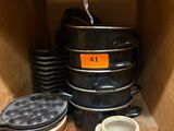 Plusieurs casseroles et poêles sont empilées sur une étagère dans une cuisine