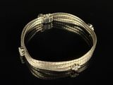 a close up of a silver bracelet on a black surface