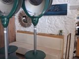 deux ventilateurs métalliques posés sur des tables dans une pièce