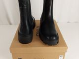 les bottes noires sont posées sur une boîte en carton, elle-même posée sur une surface blanche